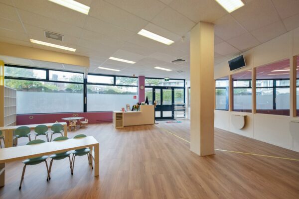 Moderne en lichte wachtruimte of binnenruimte in een kinderopvang aan de Koningin Julianalaan, met speelhoek, kinderstoelen en balie.